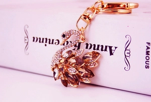 Close-up of golden swan keychain with sparkling champagne crystals on a classic book