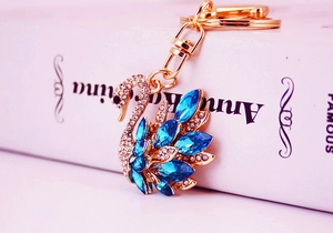 Close-up of golden swan keychain pendant with sparkling blue and clear rhinestones