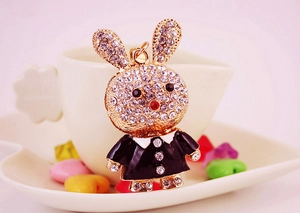 Close-up of golden bunny keychain with crystal rhinestones and black enamel dress details