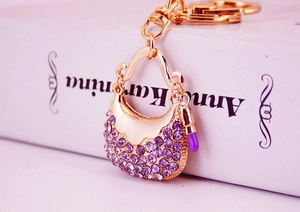 Macro shot of gold-tone handbag keychain with sparkling purple rhinestones and charm