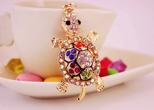 Macro detail of golden turtle keychain featuring vibrant multicolored rhinestone inlay