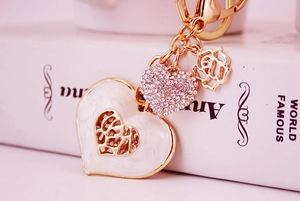 Macro detail of golden heart keychain with white enamel rose and sparkling rhinestones