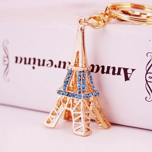 Porte-clés tour Eiffel doré avec strass bleus sur un fond rose pastel