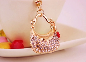 Close-up of golden rhinestone handbag keychain with a tiny red lipstick charm pendant
