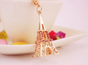Détail du porte-clés tour Eiffel doré avec strass roses accroché à une tasse blanche