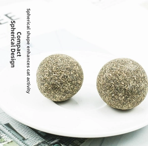 Detail of two compact catnip fiber balls for dental health on a white plate