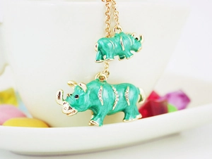 Close-up of golden necklace featuring green rhino pendants with sparkling rhinestones