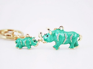 Detailed view of green enamel rhino pendants with rhinestones and gold-plated edges