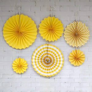 Detail of 6-piece yellow and white paper fan set with stripes and dots for party decor