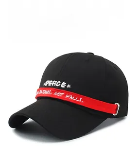 Detail of black baseball cap featuring PEACE embroidery and red decorative strap detail