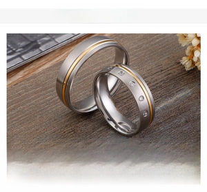 Macro shot of brushed stainless steel couple rings with gold inlay and rhinestone details
