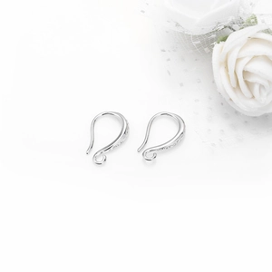 Pair of silver DIY earring hooks with sparkling textured accents on white floral backdrop