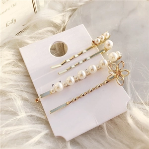 Detailed set of four elegant gold-tone hair clips with faux pearls and geometric wave designs