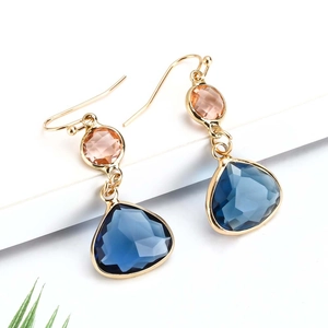 Close-up of gold-plated teardrop earrings with champagne round and deep blue crystals