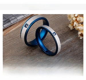 Detail of blue brushed stainless steel rings with a small inset crystal on wood