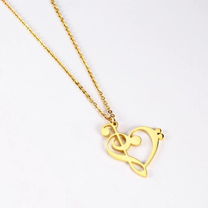 Detail view of gold 18K treble clef heart necklace pendant on clean white background