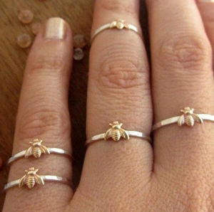Two-tone silver ring set with detailed golden bee charm worn on a finger
