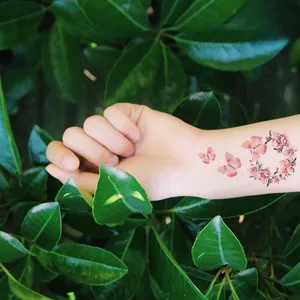 Detail of waterproof temporary tattoo with pink butterflies and floral wreath on wrist