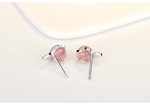 Macro detail of sweet pink strawberry crystal cat planet stud earrings in silver finish