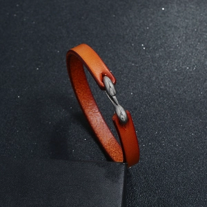 Close-up of orange leather bracelet with vintage metal buckle on black background
