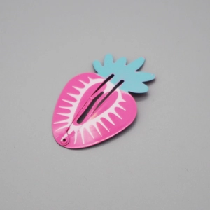 Detail of a cute strawberry-shaped pink metal snap clip with light blue leaf accents