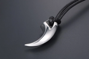 Macro shot of polished silver wolf tooth pendant with black braided rope cord
