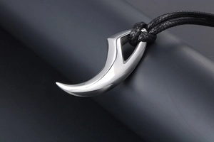 Macro shot of polished silver wolf tooth pendant with black braided rope cord