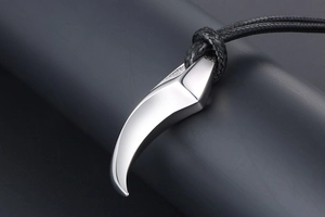 Macro shot of silver crescent tusk pendant with high gloss finish on black woven cord