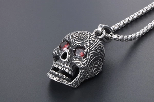 Macro detail of silver skull pendant with red eyes and intricate retro carvings on chain