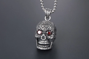 Detailed view of punk skull pendant with red gemstone eyes and silver engraved finish
