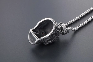 Detailed view of punk skull pendant with red stone eyes on a steel box chain