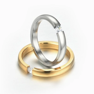 Close-up of gold and silver couple rings with small inlaid zircons on a white surface