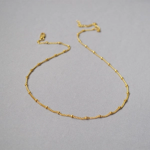 Dettaglio macro della catena a sfere in ottone placcato oro 18K con chiusura a moschettone