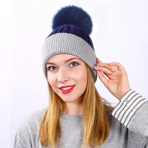 Close-up of winter knit beanie with blue pompom and grey ribbed fleece lining texture