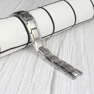 Detail of magnetic therapy steel bracelet with silver and gold links on fabric roll