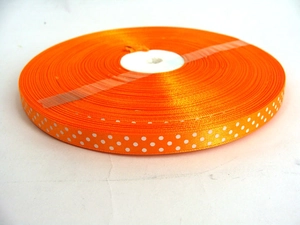 Close-up of orange polka dot polyester grosgrain ribbon roll for DIY gift wrapping and bows