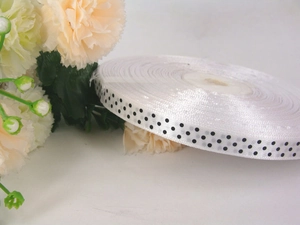 Close-up of white grosgrain ribbon with black polka dots for gift wrapping and DIY crafts