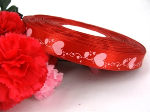 Macro shot of red satin ribbon with pink heart patterns for gift wrapping and DIY crafts