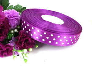 Macro view of purple polka dot ribbon roll with white dots and decorative flowers
