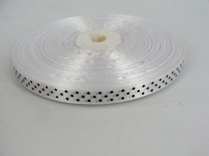 Detailed view of white grosgrain ribbon with black polka dots on a roll for DIY gift wrapping