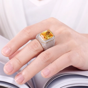 Detailed close-up of a luxury iced-out silver ring featuring a large square yellow zircon