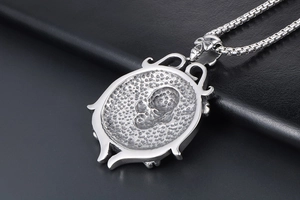 Macro shot of silver vintage skull rudder pendant with textured steel on black leather