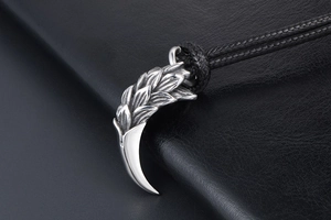 Macro shot of silver dragon claw pendant with scale texture on black leather background