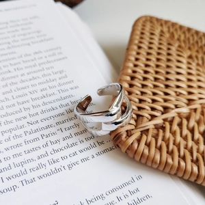 Close-up of a 925 sterling silver knotted open ring on a book and woven mat