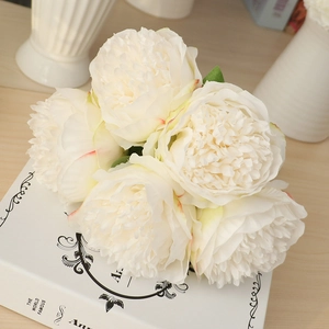 Top view detail of creamy white artificial silk peonies on decorative vintage book