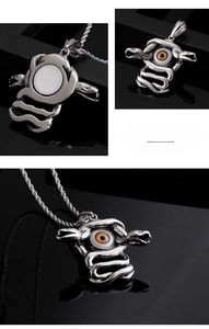 Macro detail of gothic snake pendant with brown evil eye in polished stainless steel