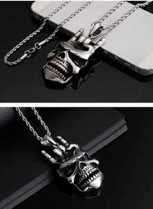 Détail du pendentif crâne rock argenté avec chaîne torsadée sur surface noire