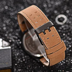 Detail of brown matte leather watch strap with hand-stitched edges and black metal buckle