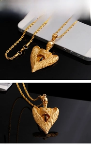 Macro view of gold stainless steel skull pendant with angel wings and amber bead