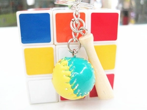 Close-up of mini wooden baseball bat and leather softball keychain on silver ring